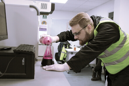 lab worker pours chemicals into a container during the creation of a new product